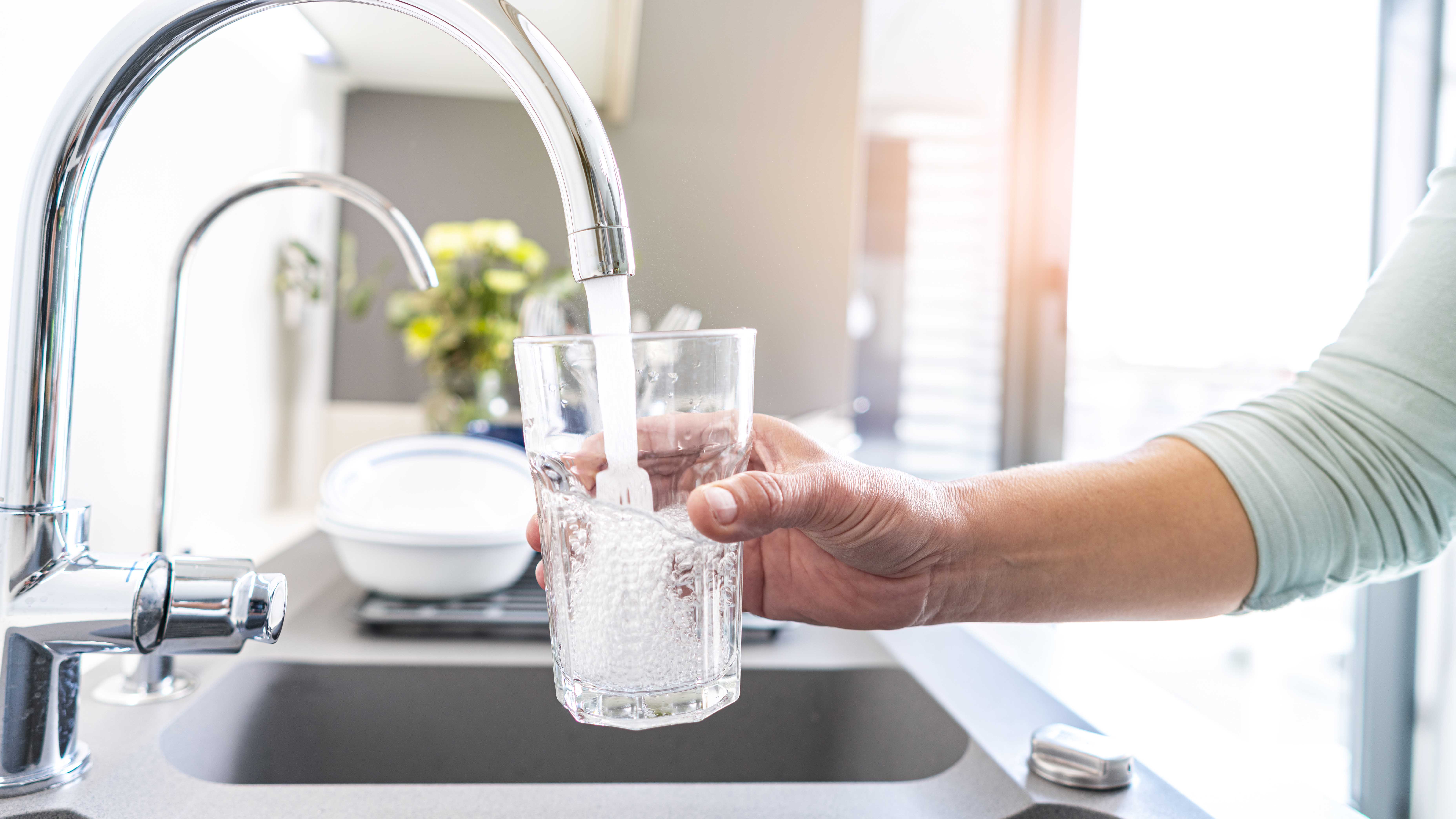 A person filling glass with tap water.