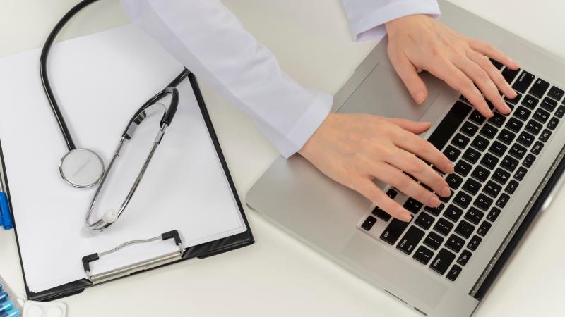 Lääkärin kädet tietokoneen näppäimistöllä.