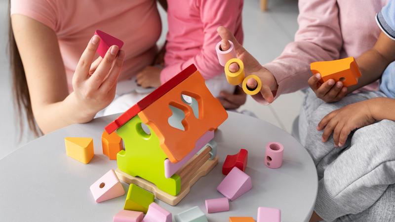 Two adults and a child are playing with blocks.